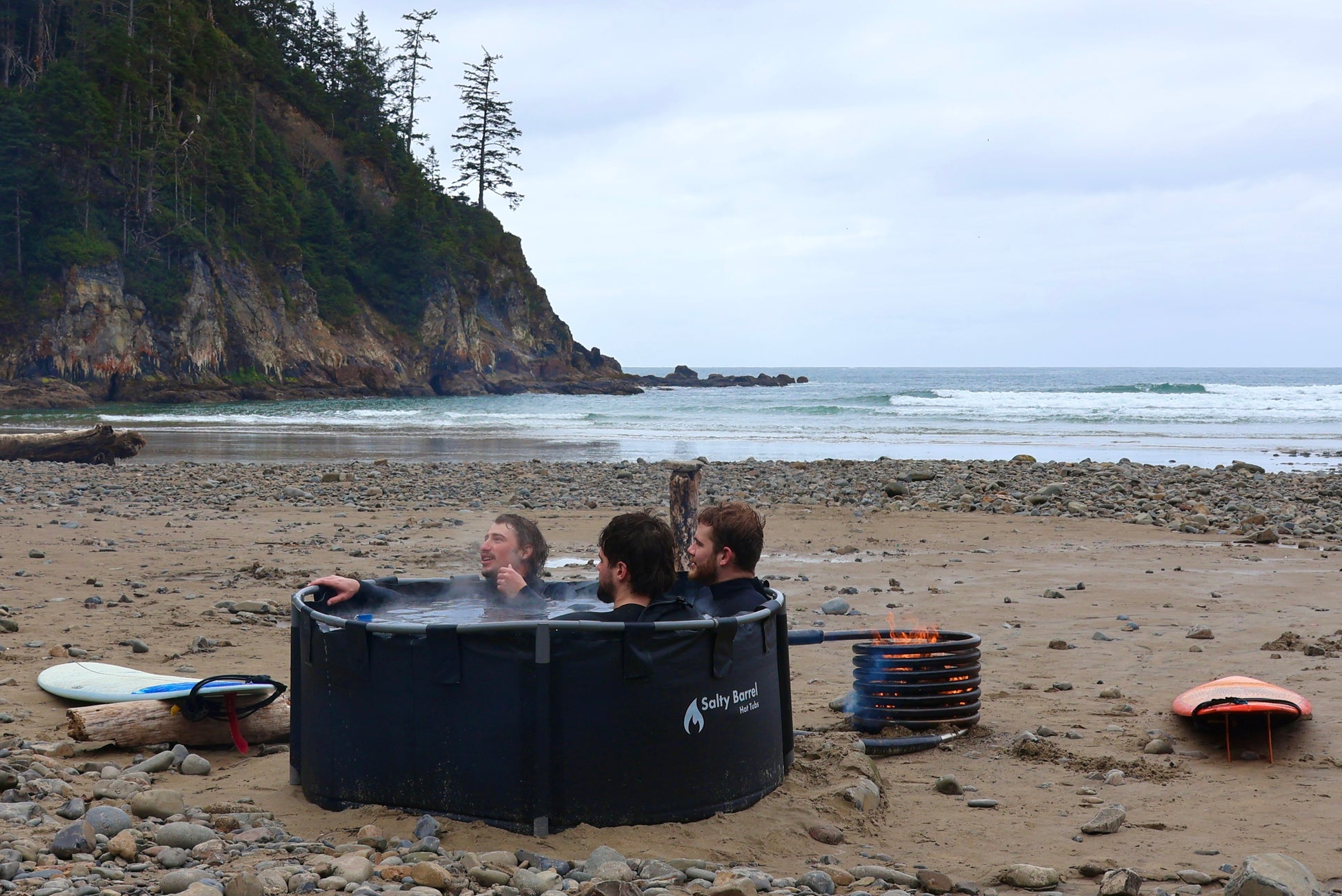 Surfers warming up in off grid spa at the beach